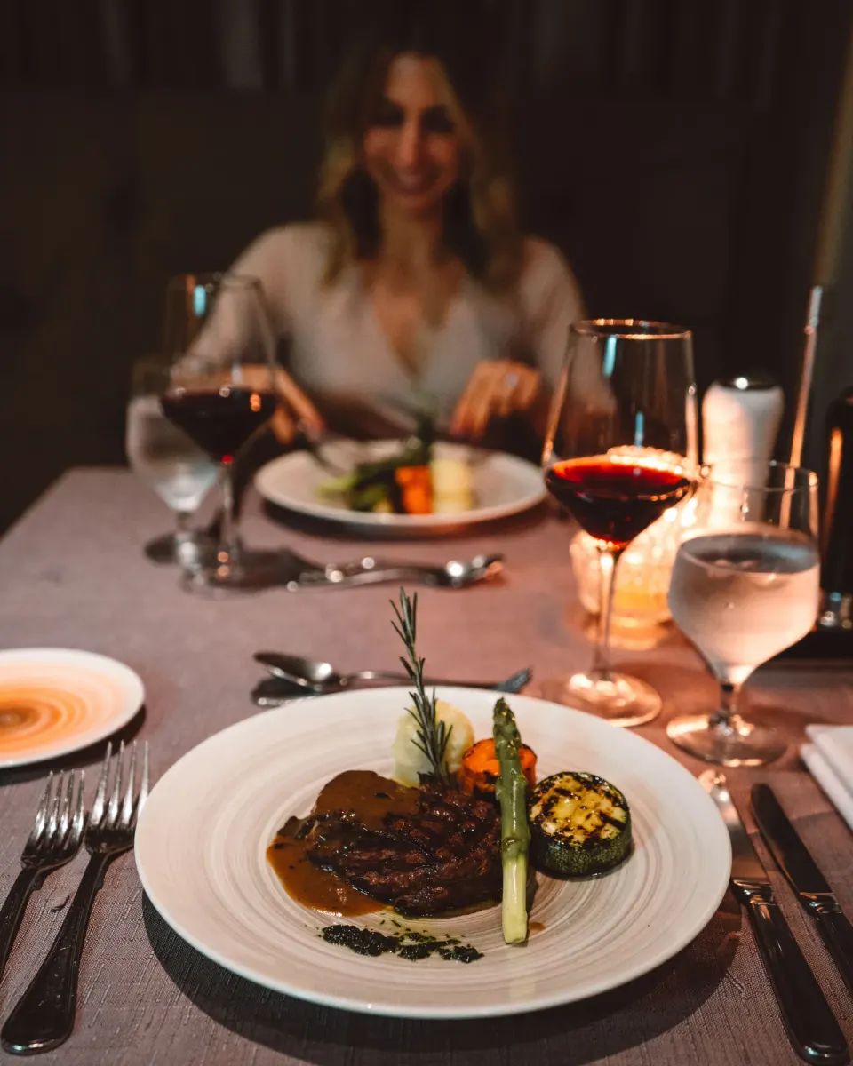 Candlelit dinner table with steak, vegetables, and red wine at Hard Rock Hotel Cancun.
