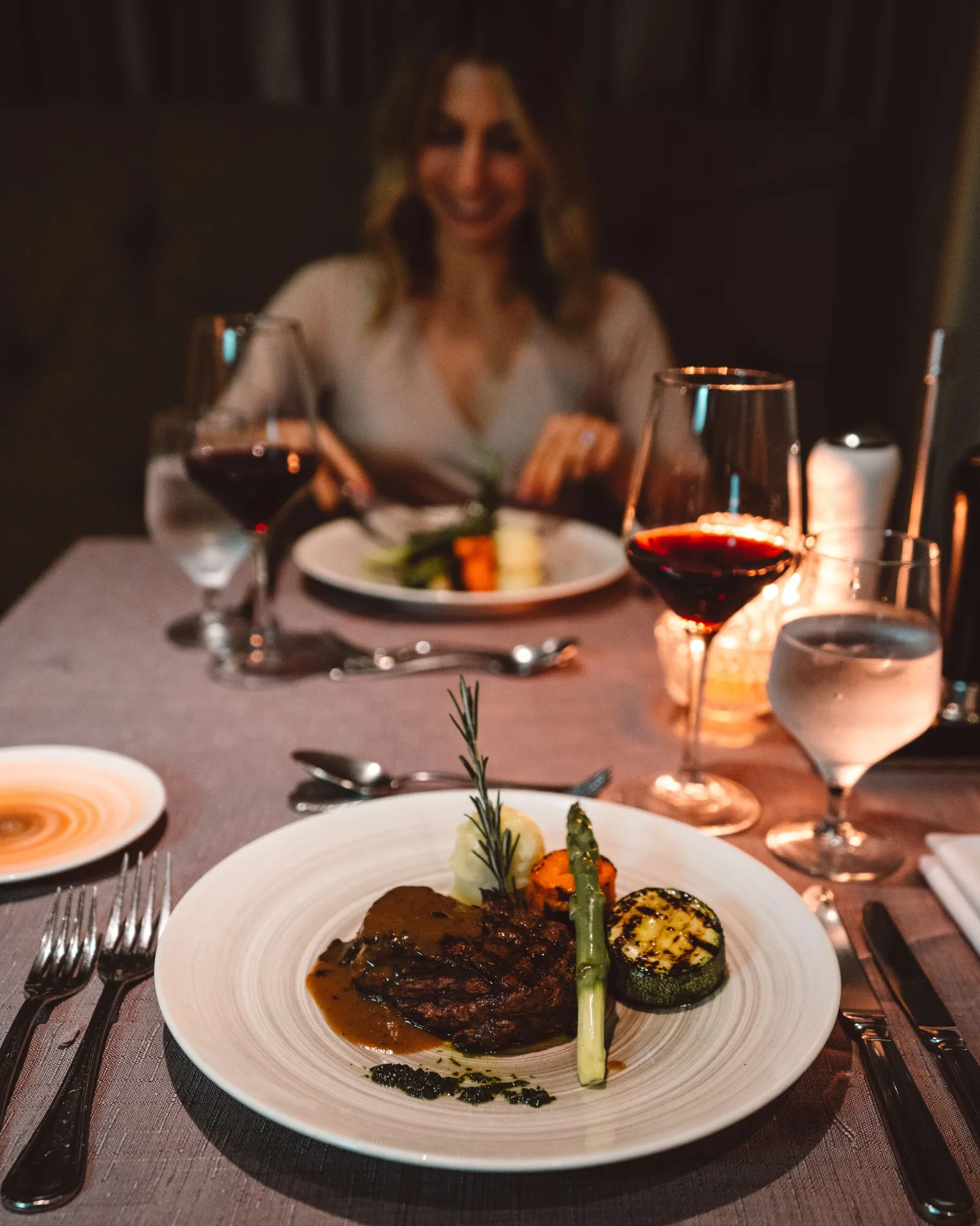 Candlelit dinner table with steak, vegetables, and red wine at Hard Rock Hotel Cancun.