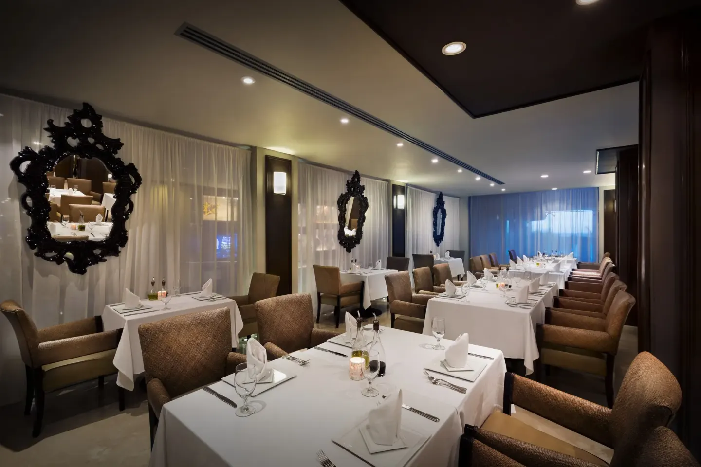 Elegant dining room with white tablecloths and ornate mirrors at Hard Rock Hotel Cancun.