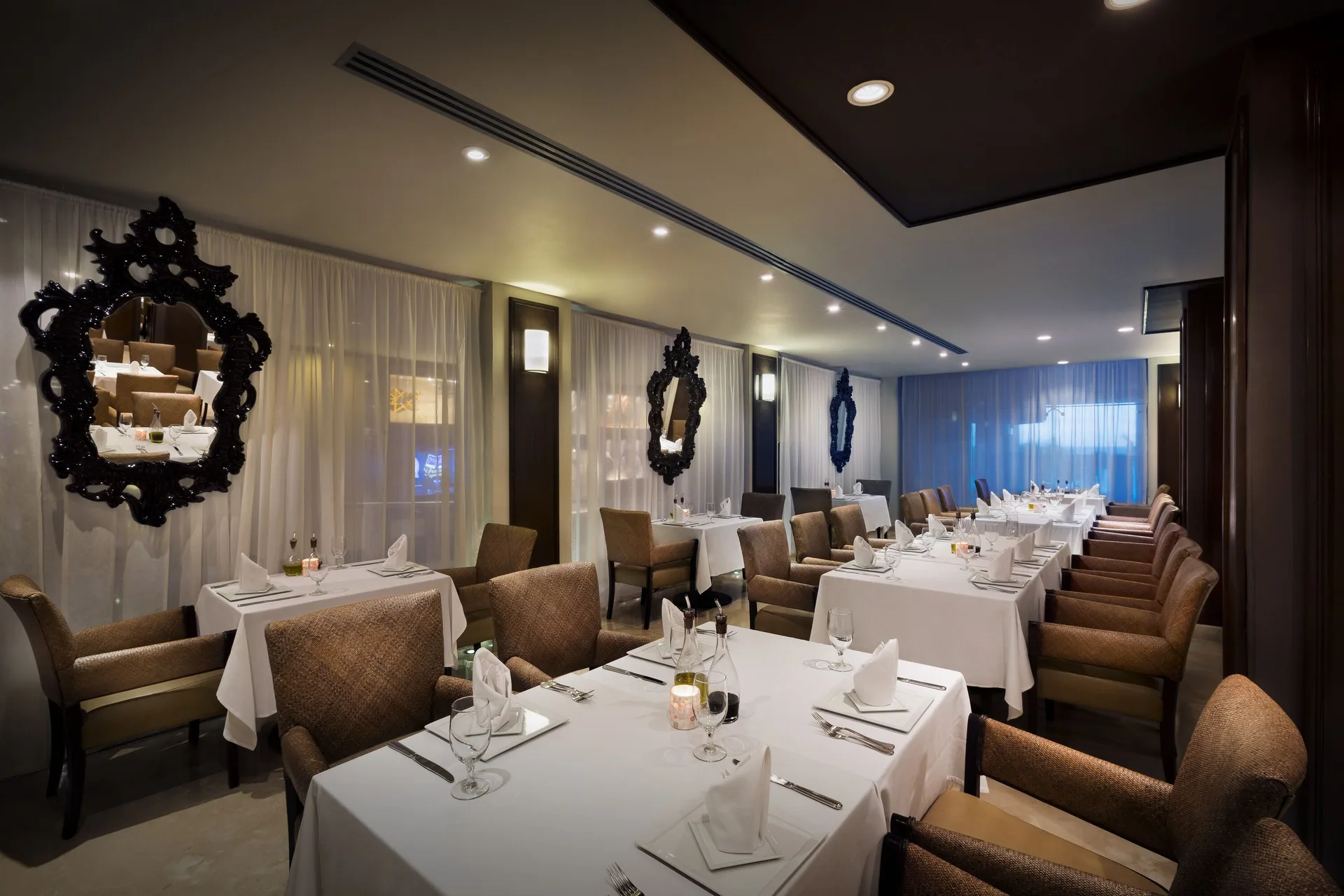 Elegant dining room with white tablecloths and ornate mirrors at Hard Rock Hotel Cancun.