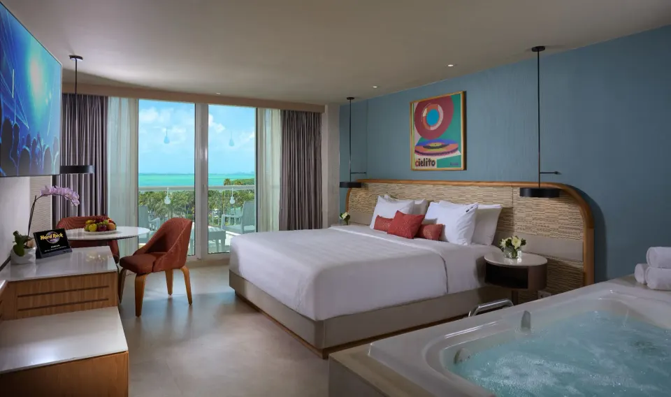 Deluxe Lagoon View king bed, balcony doors and in-room tub at Hard Rock Hotel Cancun.
