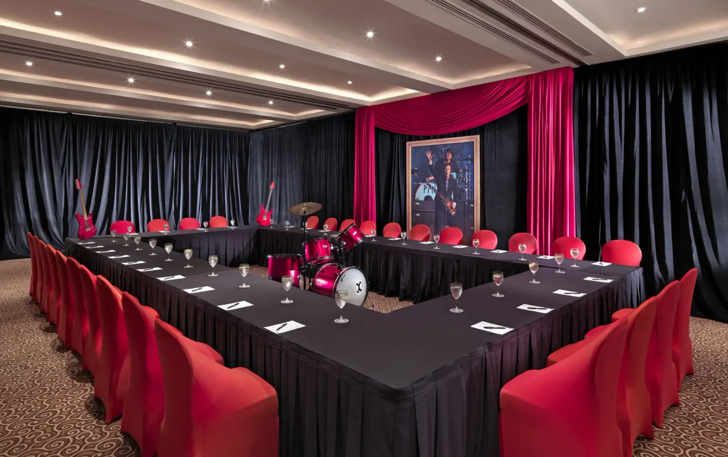 Meeting room with red chairs, black drapes, and a drum kit at Hard Rock Hotel Cancun.