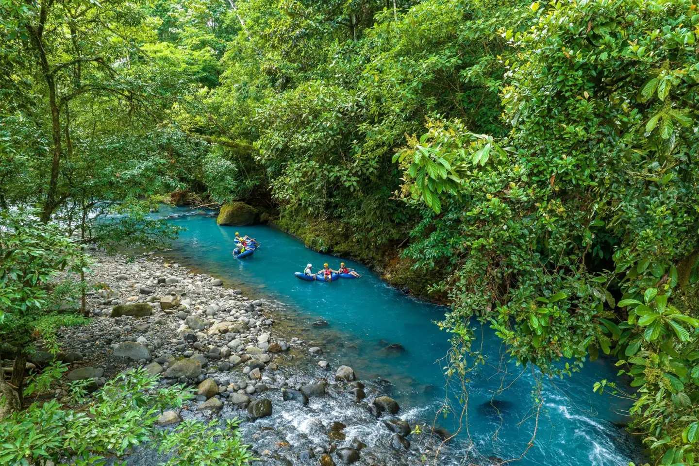 Rafting groups floating on the blue river through rainforest at Hideaway Rio Celeste.