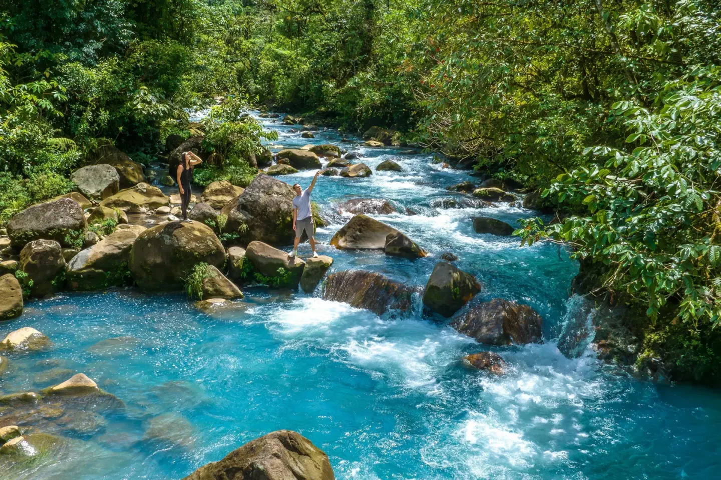 Bright blue river with rocks and forest near Hideaway Rio Celeste.