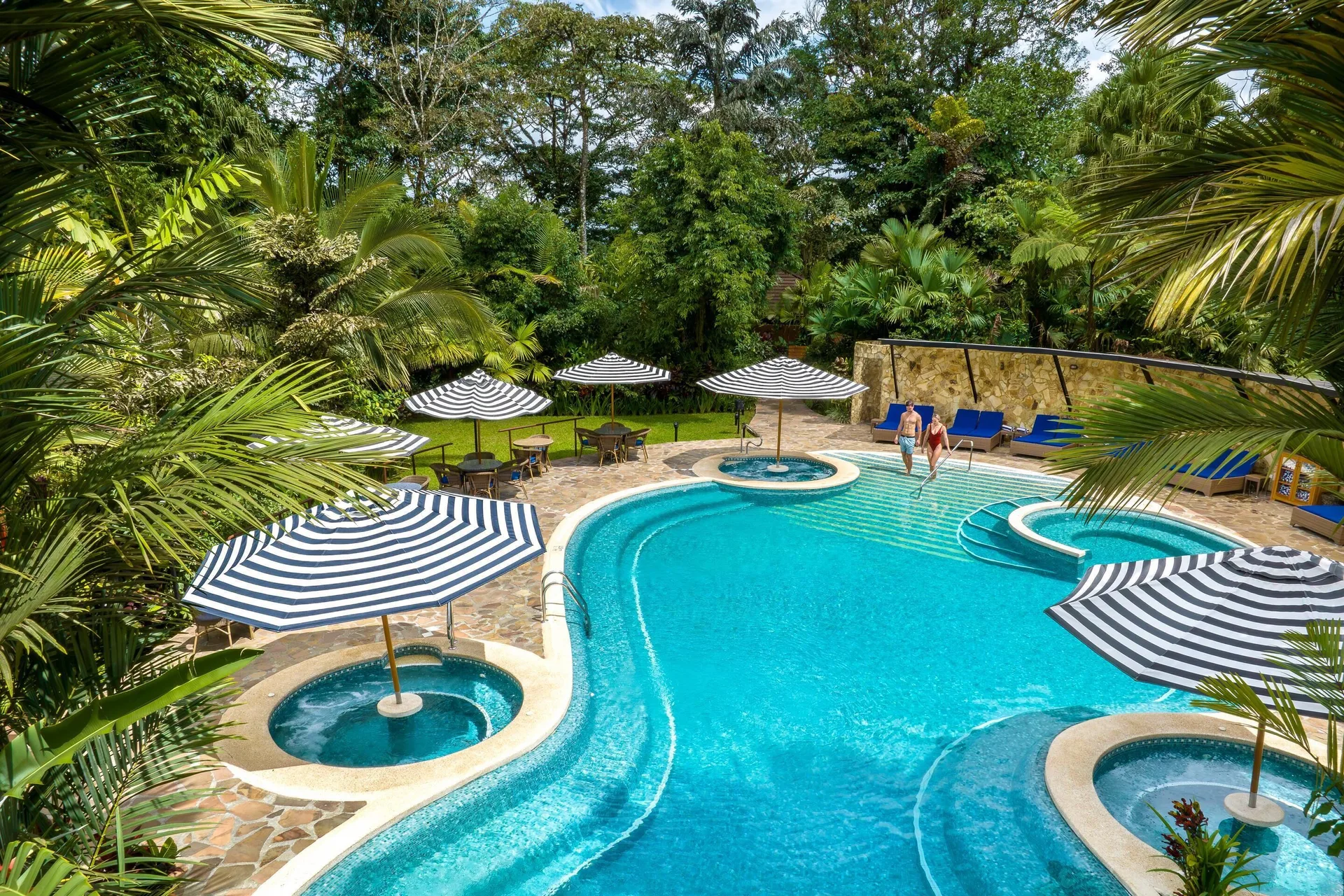Curved outdoor pool with striped umbrellas at Hideaway Rio Celeste.
