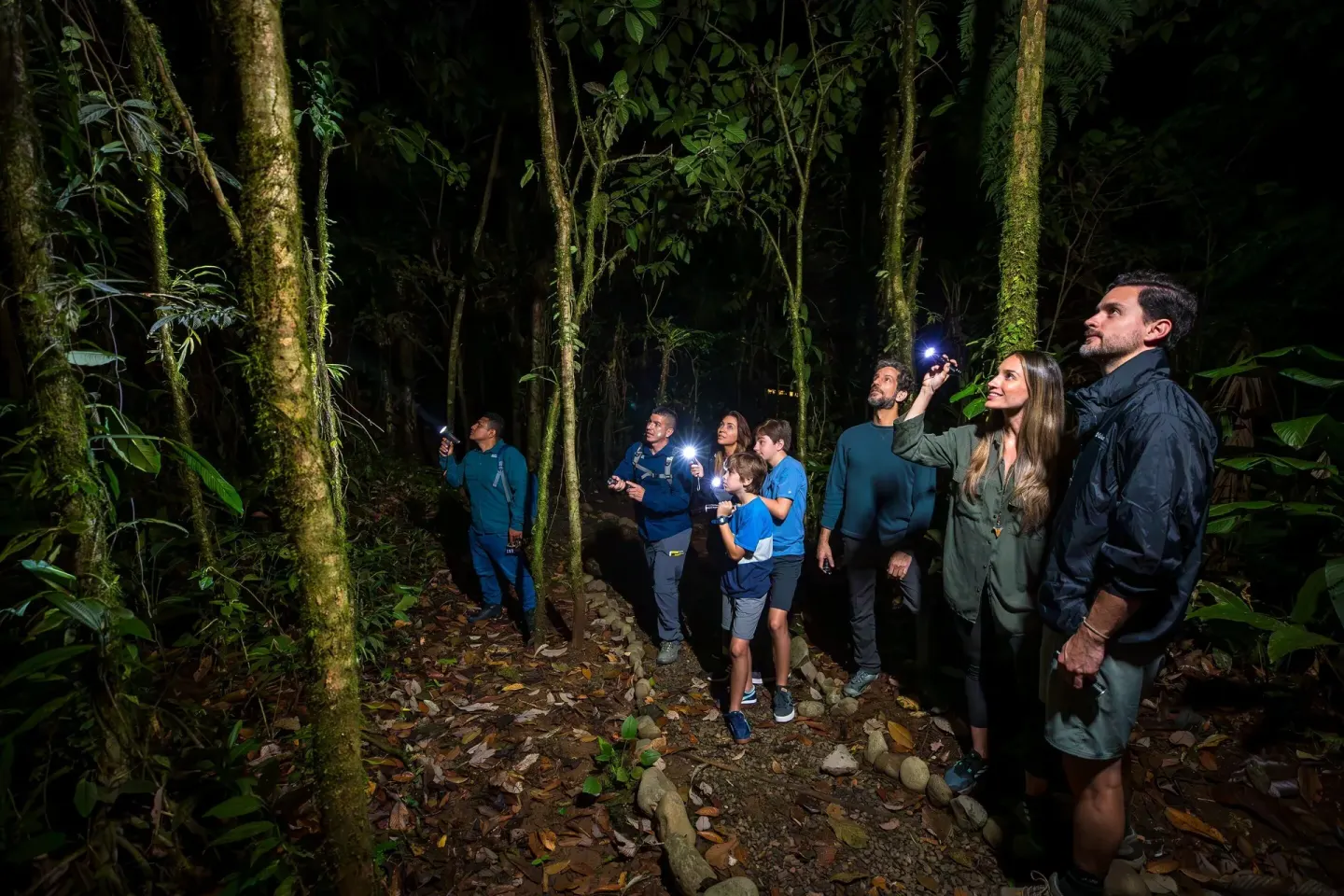 Guests using flashlights on a nighttime forest walk at Hideaway Rio Celeste.