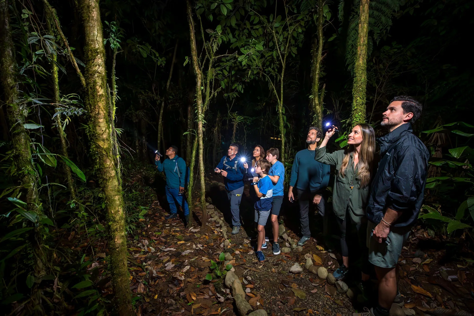 Guests using flashlights on a nighttime forest walk at Hideaway Rio Celeste.