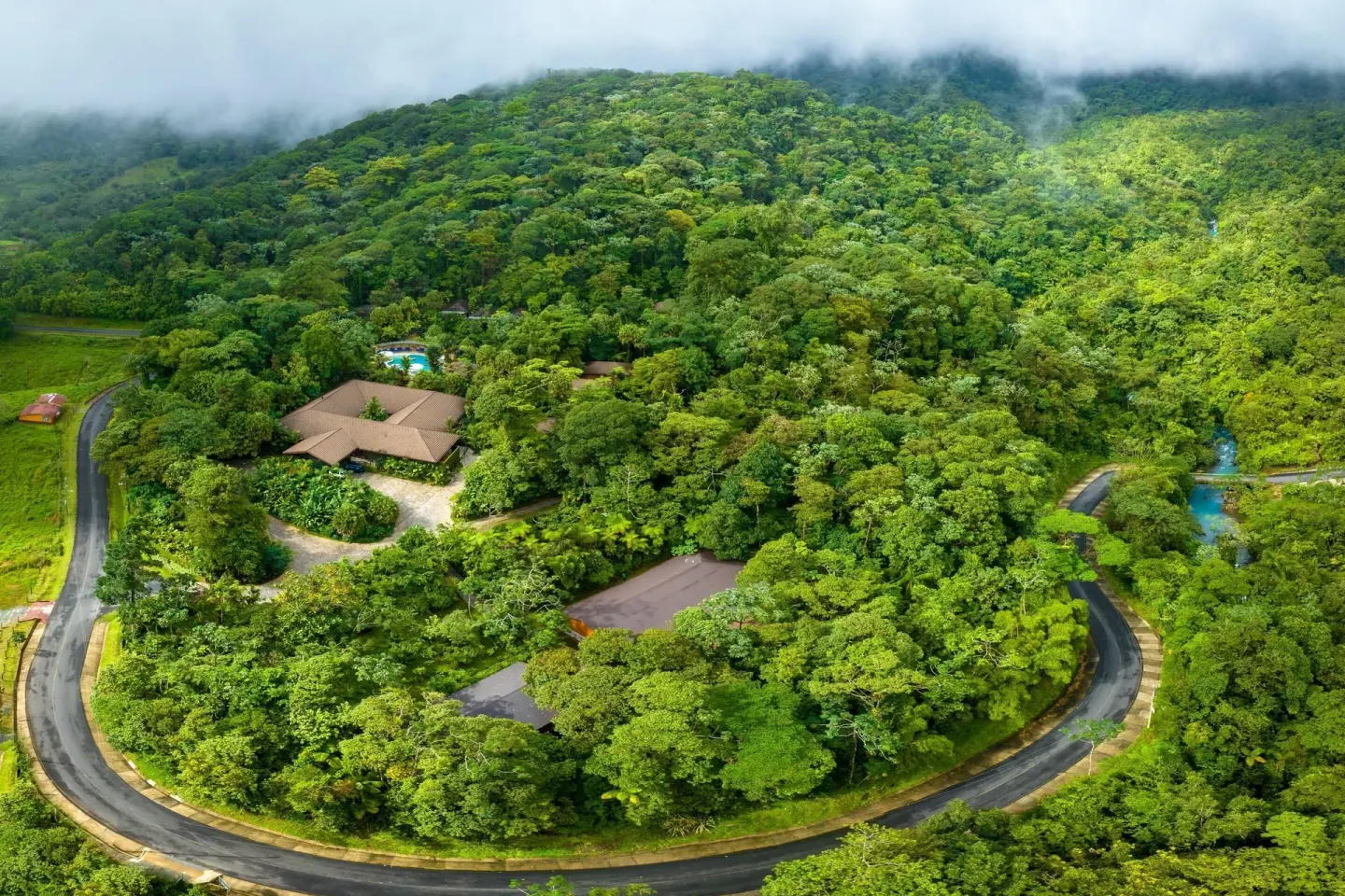 Aerial view of Hideaway Rio Celeste surrounded by rainforest and hills.