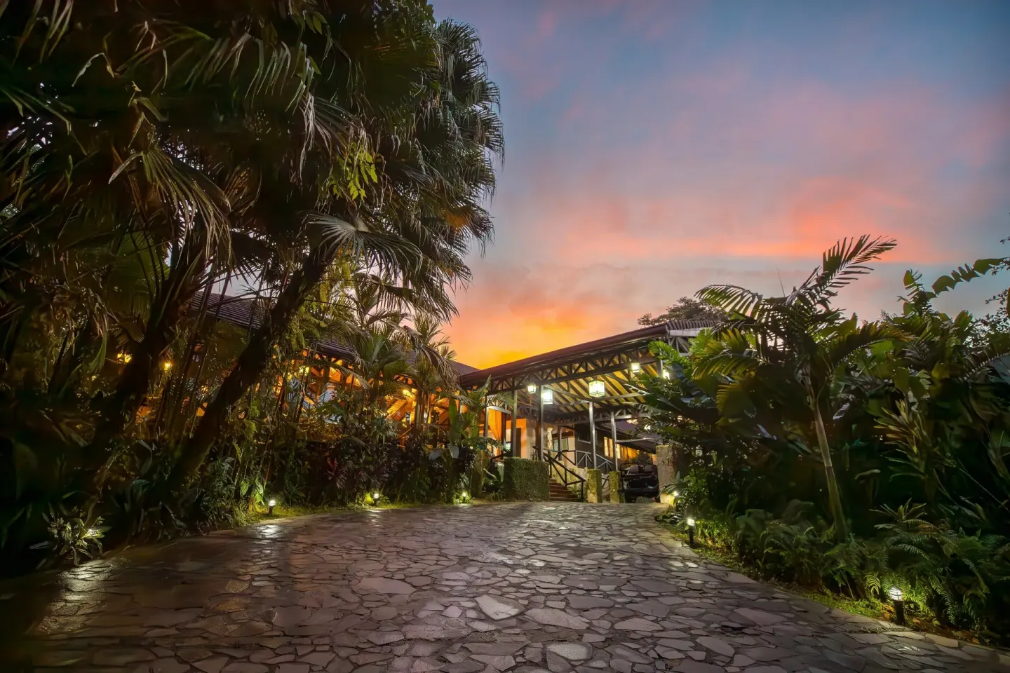 Stone driveway and warmly lit resort building at sunset at Hideaway Rio Celeste.