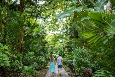 Couple walking a stone path through tropical gardens at Hideaway Rio Celeste.