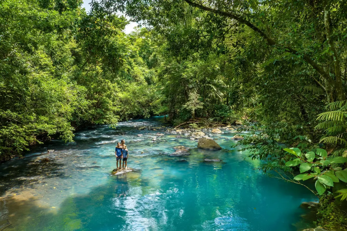 Wide view of guests in a turquoise rainforest river at Hideaway Rio Celeste.