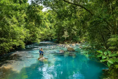 Wide view of guests in a turquoise rainforest river at Hideaway Rio Celeste.