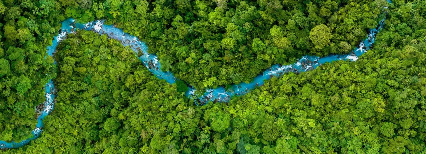 Aerial view of a winding blue river through rainforest at Hideaway Rio Celeste.