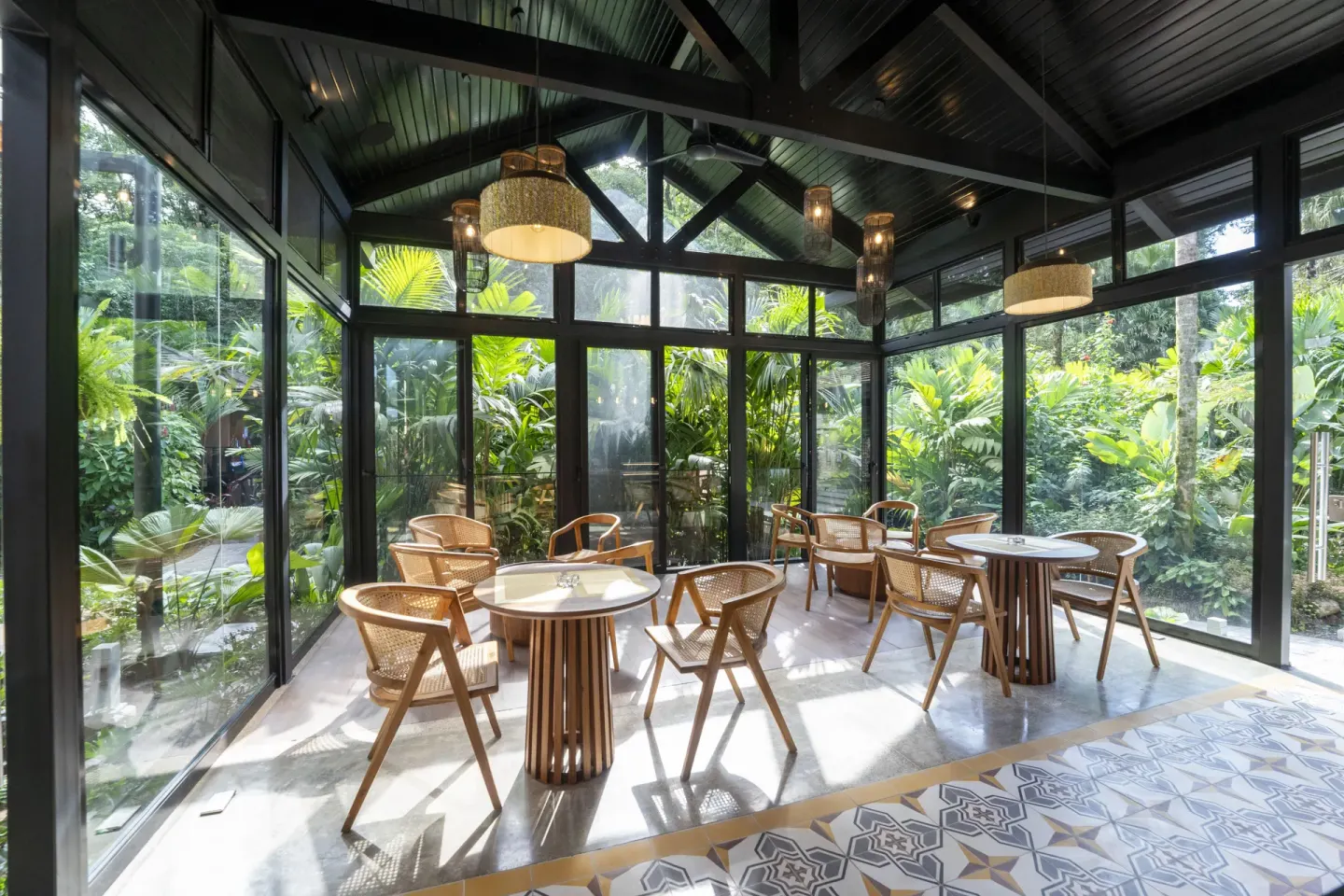 Glass-walled cafe seating area surrounded by tropical plants at Hideaway Rio Celeste.
