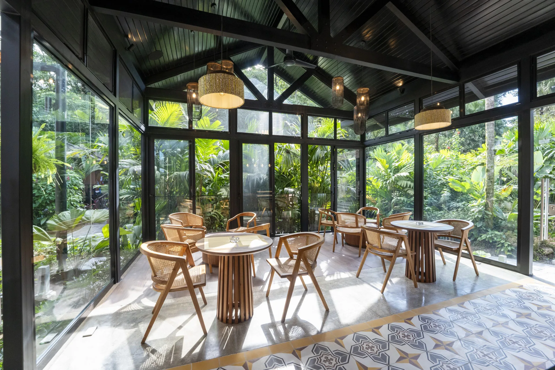 Glass-walled cafe seating area surrounded by tropical plants at Hideaway Rio Celeste.