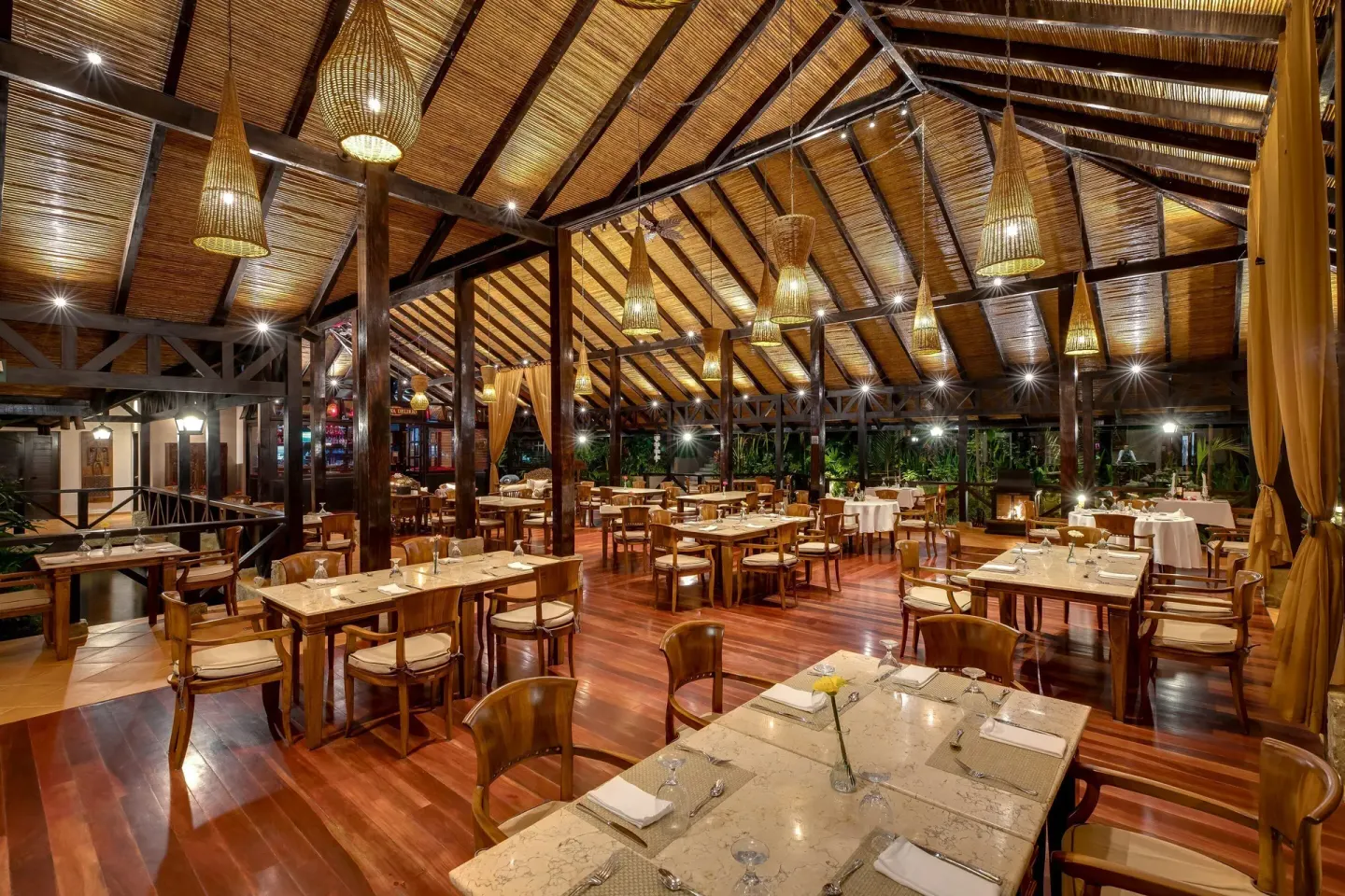Set dining tables in a large timber-roofed restaurant at Hideaway Rio Celeste.