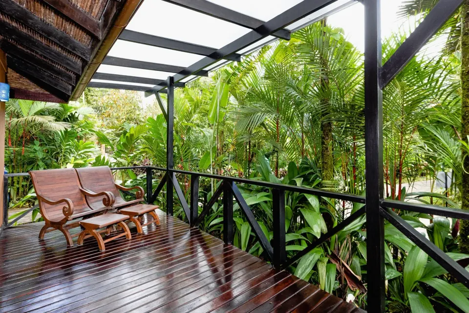 Garden View Casita at Hideaway Rio Celeste with a covered wooden terrace and two chairs facing tropical plants.