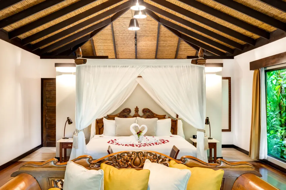 Garden View Casita at Hideaway Rio Celeste with a decorated canopy bed and carved sofa in the foreground.