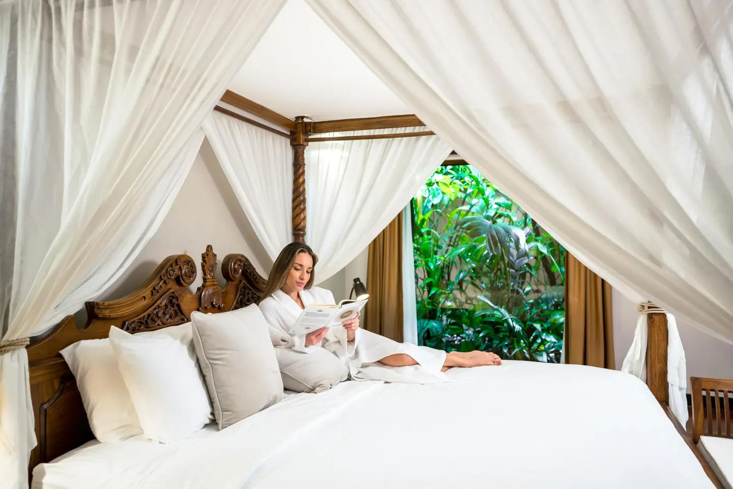 Garden View Casita at Hideaway Rio Celeste with a guest reading in the white-draped canopy bed.