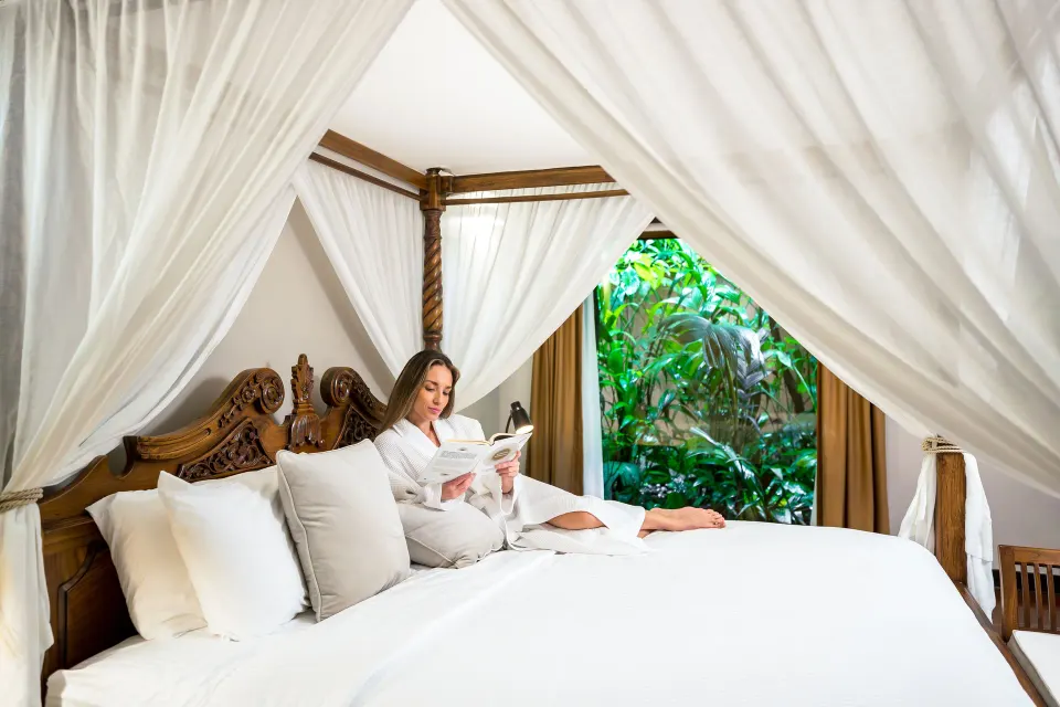Garden View Casita at Hideaway Rio Celeste with a guest reading in the white-draped canopy bed.