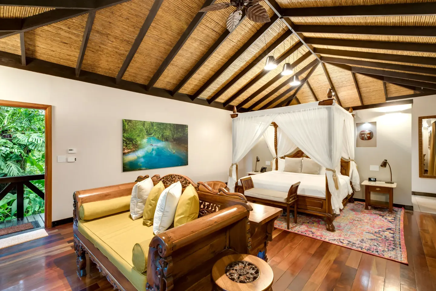 Garden View Casita at Hideaway Rio Celeste with canopy bed, carved daybed, artwork, and open garden door.