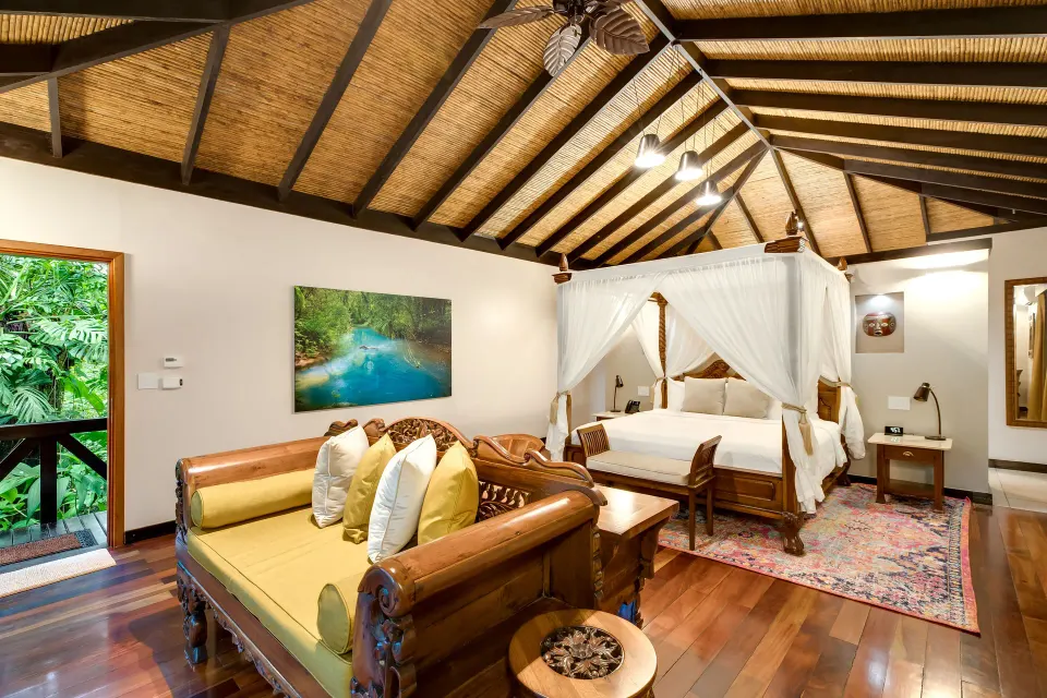 Garden View Casita at Hideaway Rio Celeste with canopy bed, carved daybed, artwork, and open garden door.