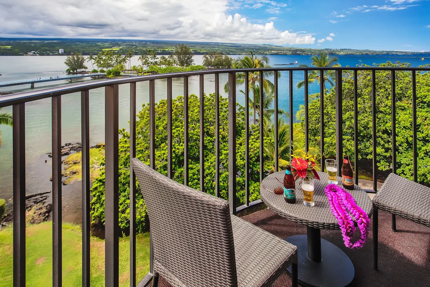 Balcony table with drinks and leis overlooking Hilo Hawaiian Hotel at Hilo Hawaiian Hotel.