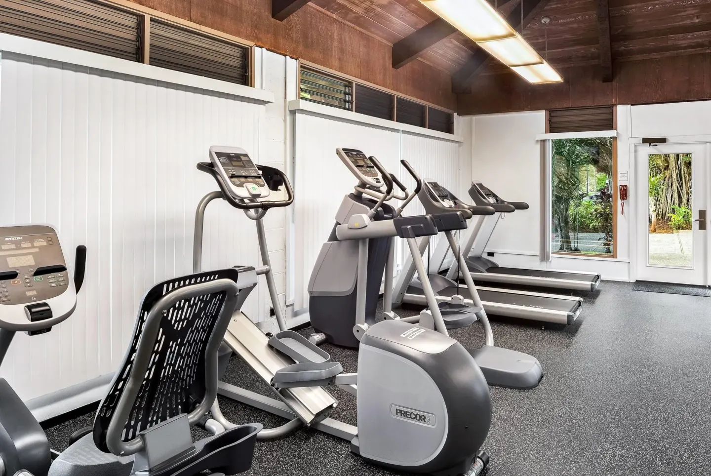 Fitness room cardio machines facing white walls and windows at Hilo Hawaiian Hotel.