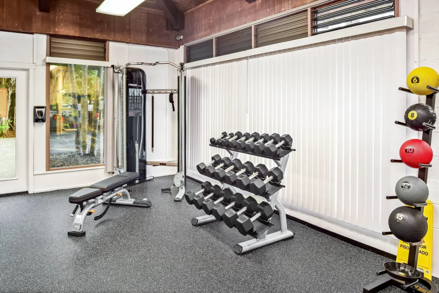 Fitness room with dumbbell rack, cable machine, and medicine balls at Hilo Hawaiian Hotel.