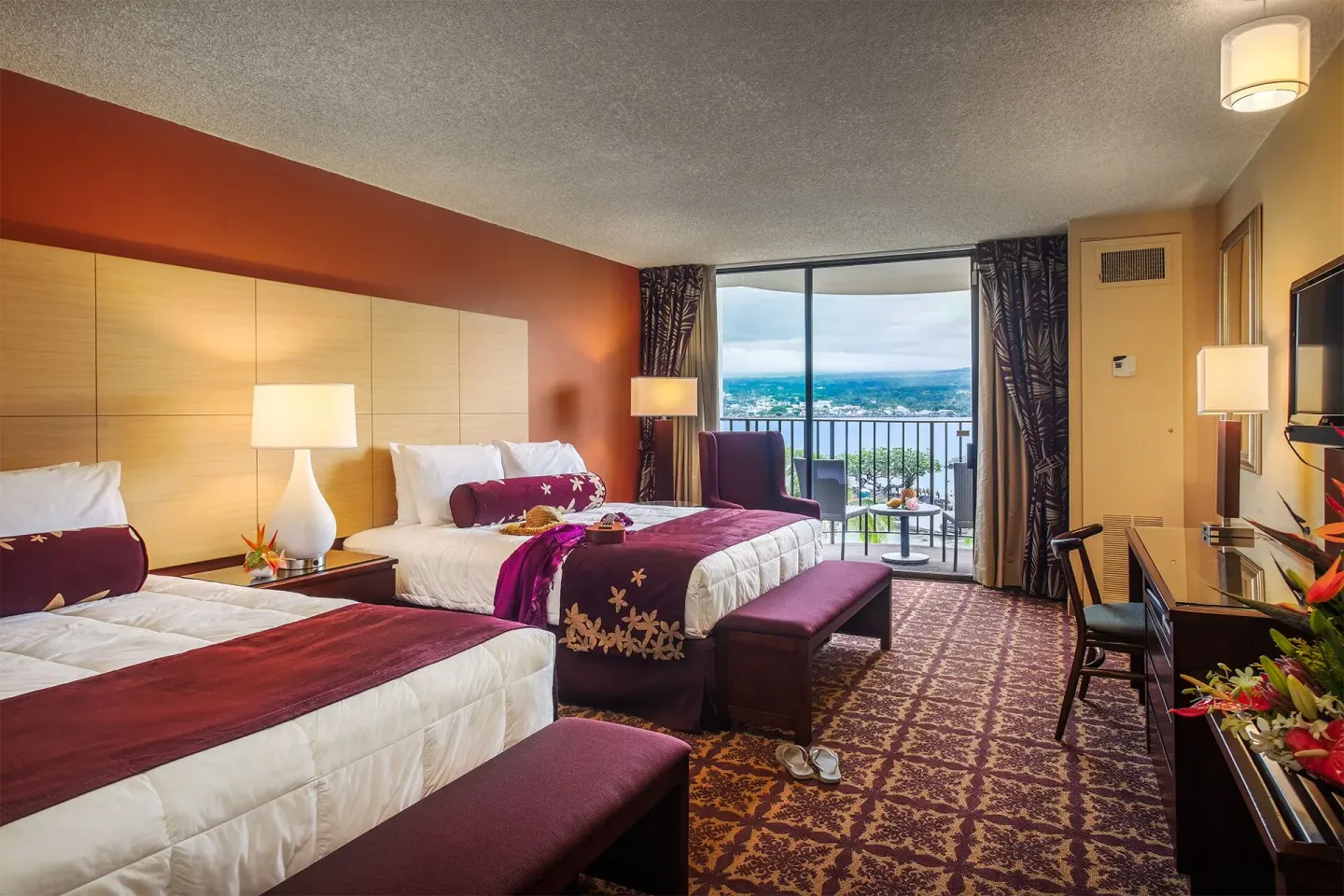 Guest room with two beds, balcony, and distant water view at Hilo Hawaiian Hotel.