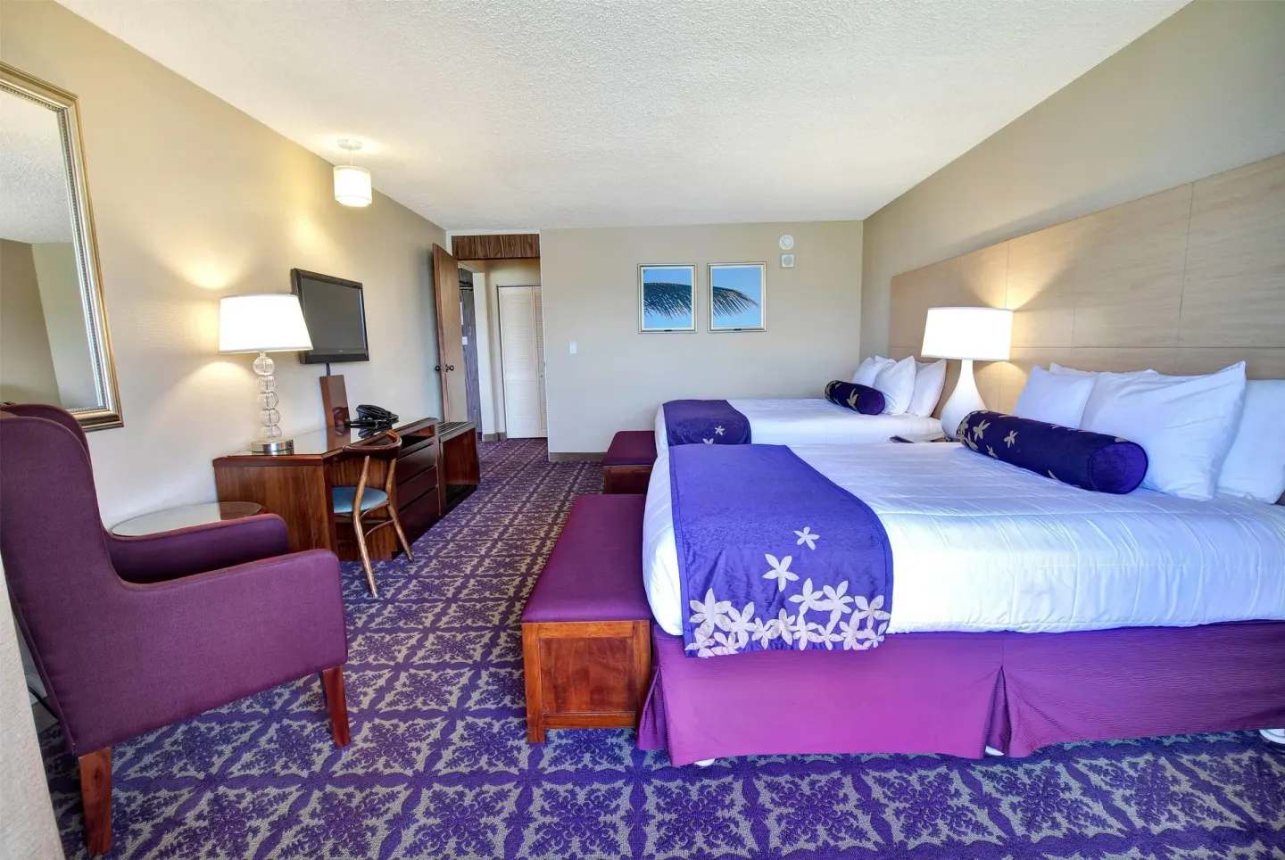Two-bed guest room with purple accents and seating at Hilo Hawaiian Hotel.