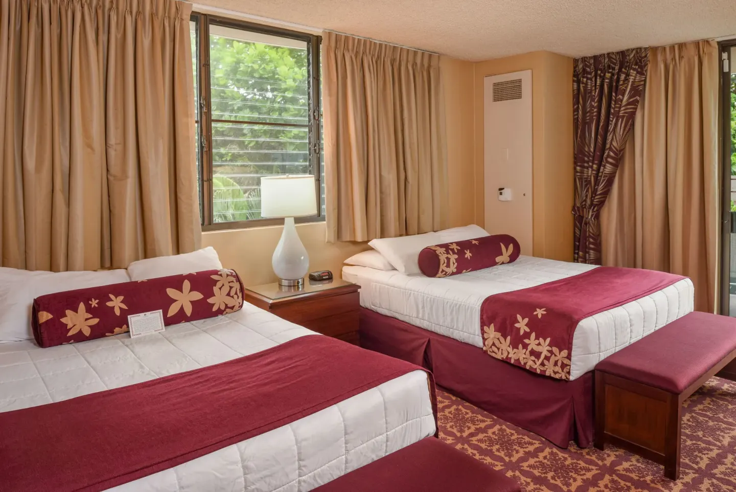 Guest room with two beds, window, and burgundy accents at Hilo Hawaiian Hotel.