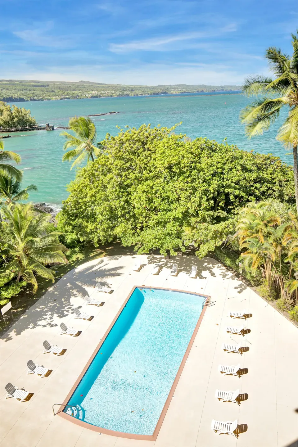 Pool with lounge chairs overlooking Hilo Hawaiian Hotel at Hilo Hawaiian Hotel.