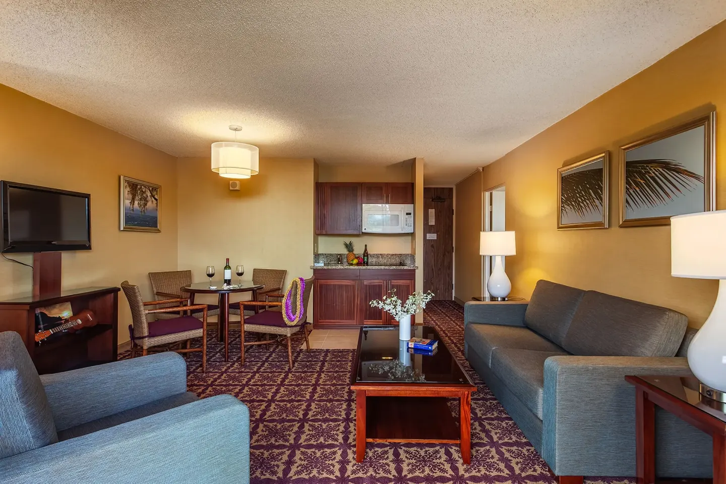 Suite living area with kitchenette, dining table, and sofa at Hilo Hawaiian Hotel.