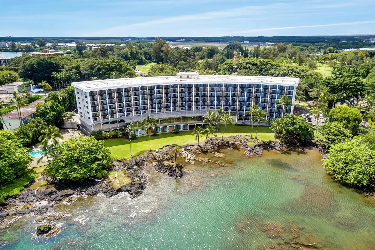 Aerial view of the waterfront hotel building and rocky shoreline at Hilo Hawaiian Hotel.