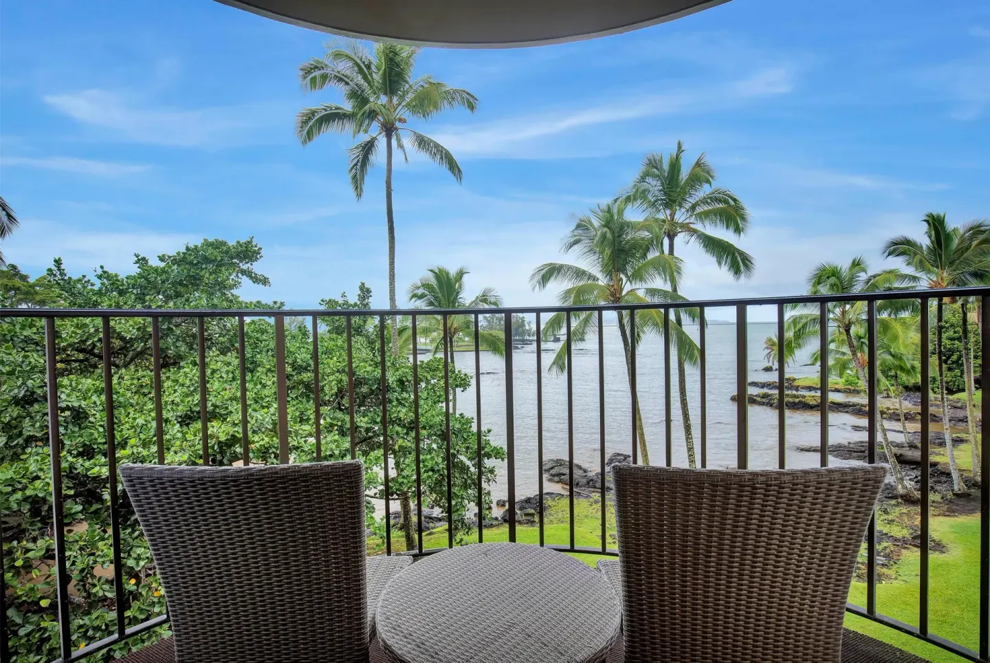 Ocean view balcony with two wicker chairs at Hilo Hawaiian Hotel.