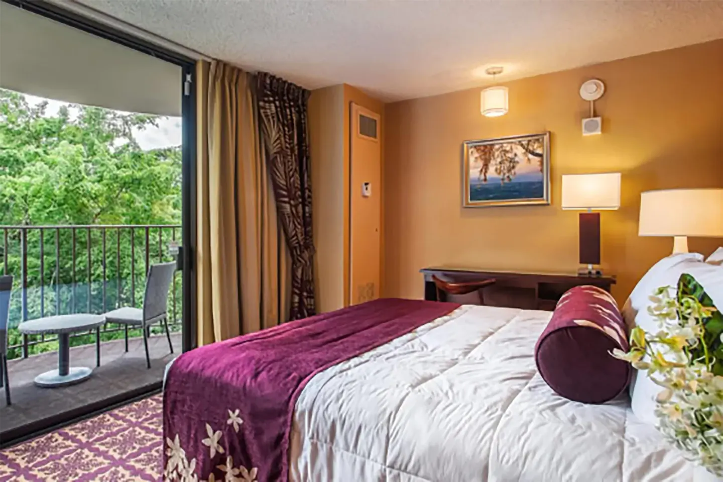 Junior suite bedroom with balcony and banyan view at Hilo Hawaiian Hotel.