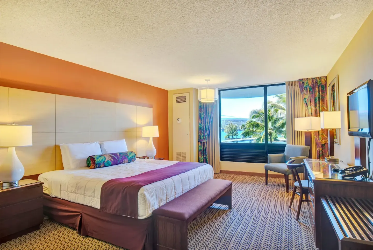 Ocean view guest room with king bed and seating area at Hilo Hawaiian Hotel.