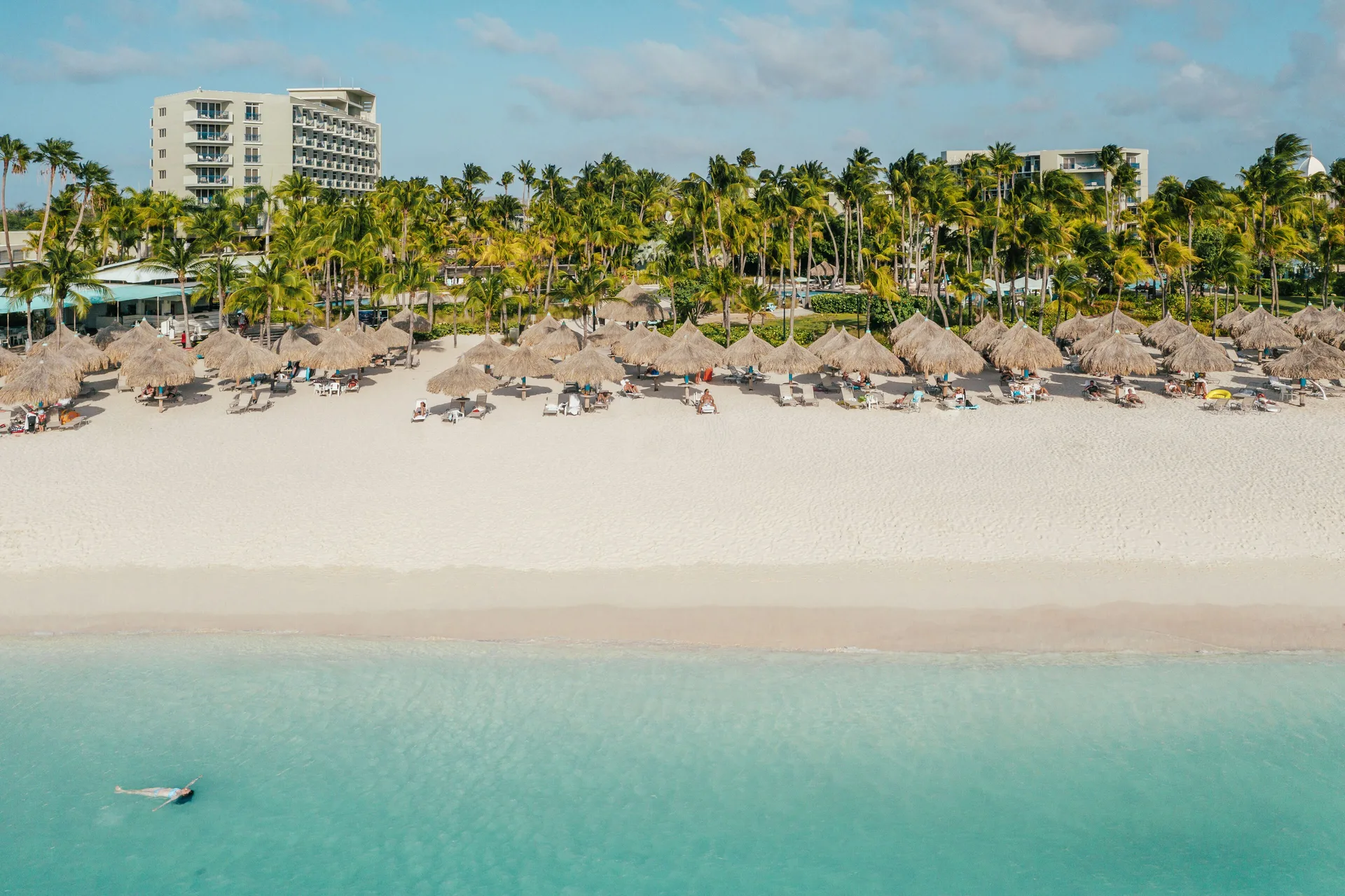 Beach palapas and turquoise water at Hilton Aruba Caribbean Resort and Casino.