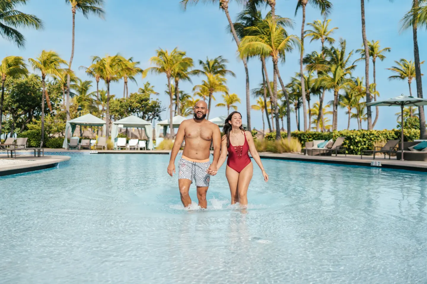 Couple walking in the shallow resort pool at Hilton Aruba Caribbean Resort and Casino.