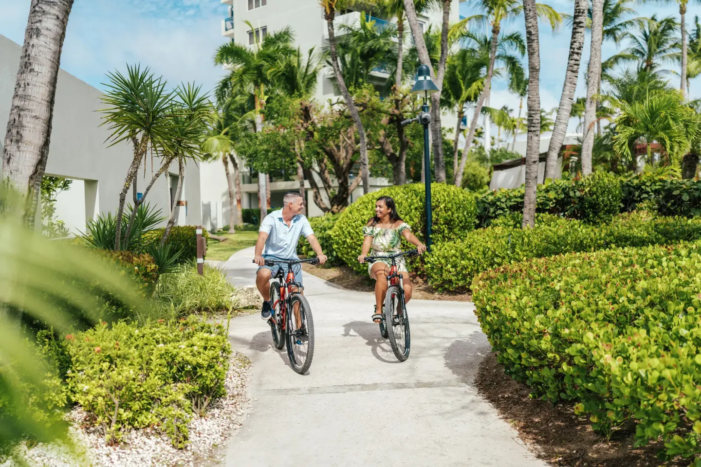 Guests riding bicycles on a garden path at Hilton Aruba Caribbean Resort and Casino.