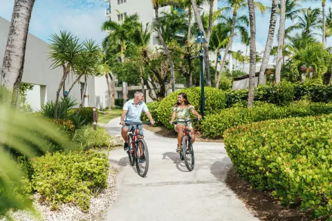 Guests riding bicycles on a garden path at Hilton Aruba Caribbean Resort and Casino.