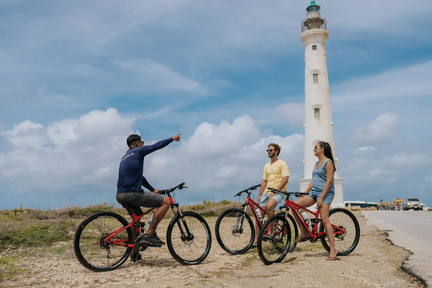 Cyclists pause by a white lighthouse near Hilton Aruba Caribbean Resort and Casino.
