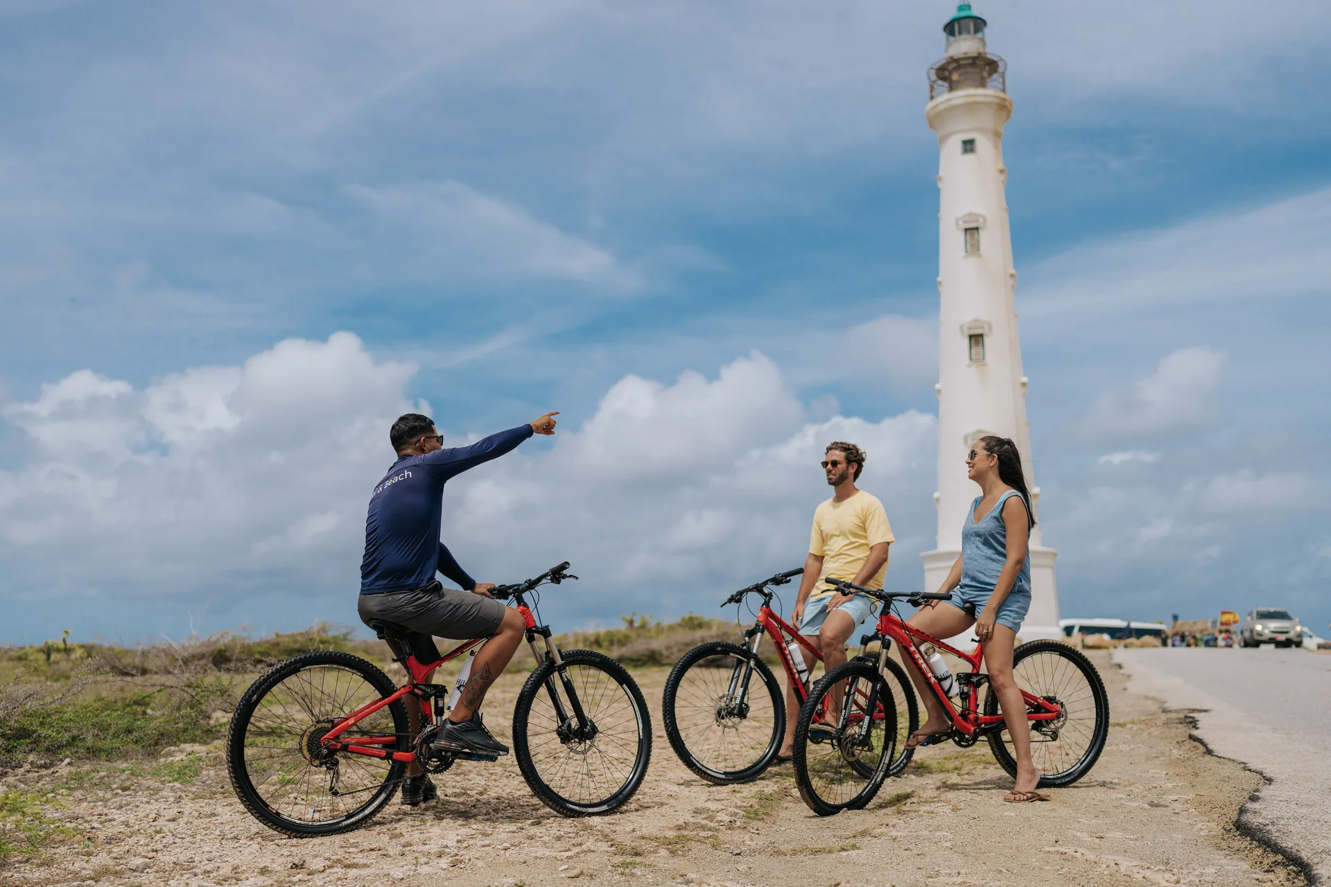 Cyclists pause by a white lighthouse near Hilton Aruba Caribbean Resort and Casino.