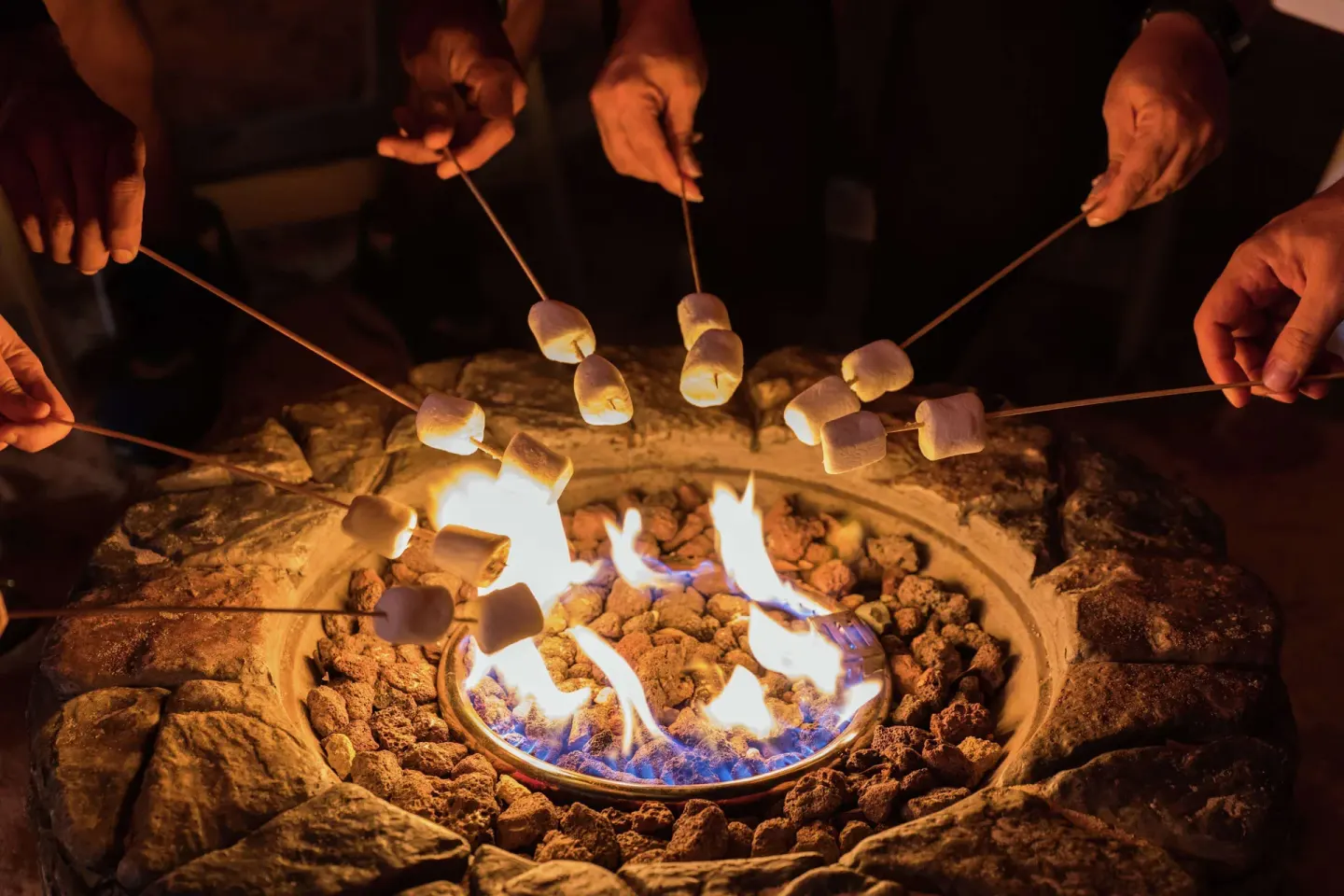Guests roasting marshmallows over a fire pit at Hilton Aruba Caribbean Resort and Casino.