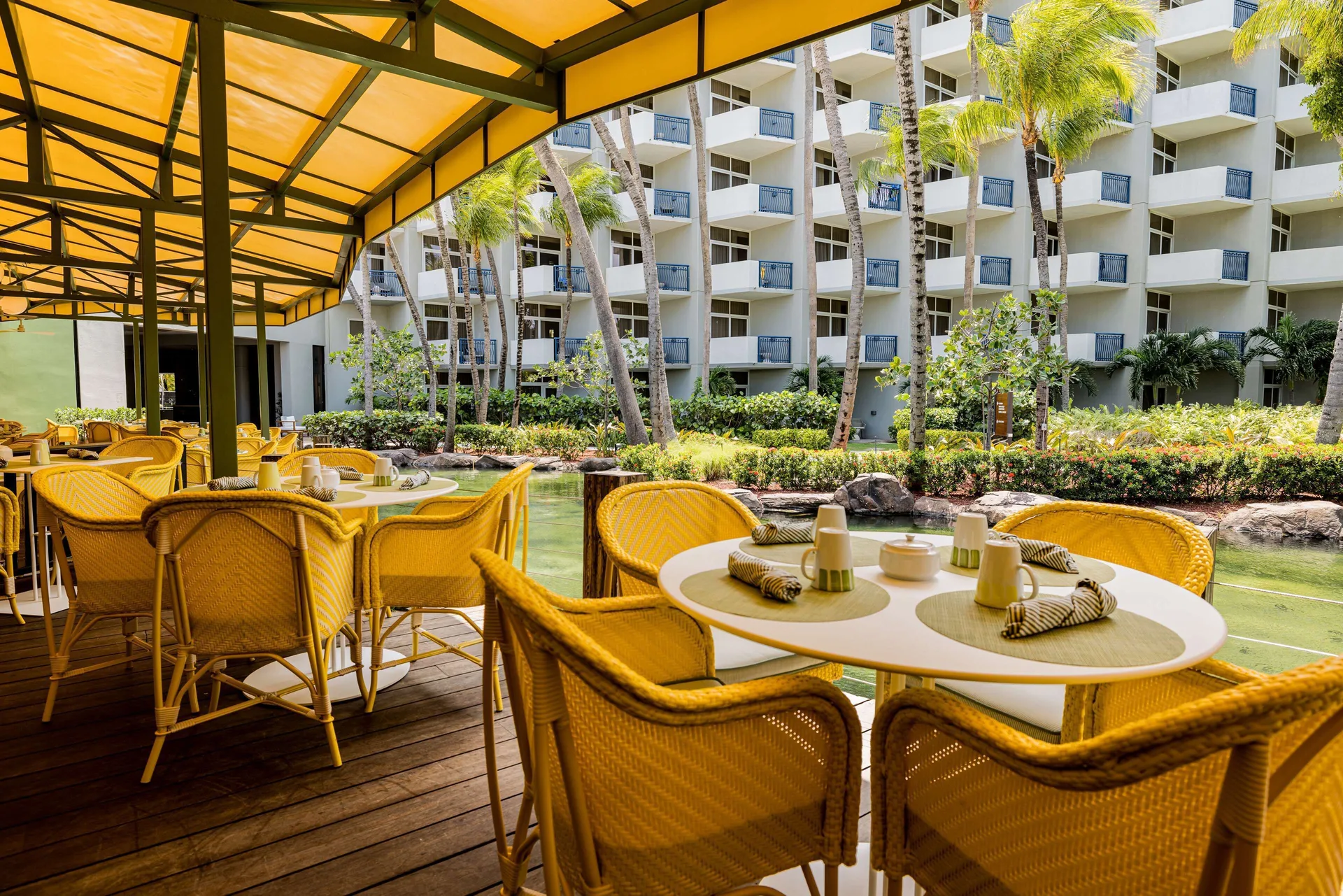 Lagoon-side restaurant terrace with yellow chairs at Hilton Aruba Caribbean Resort and Casino.
