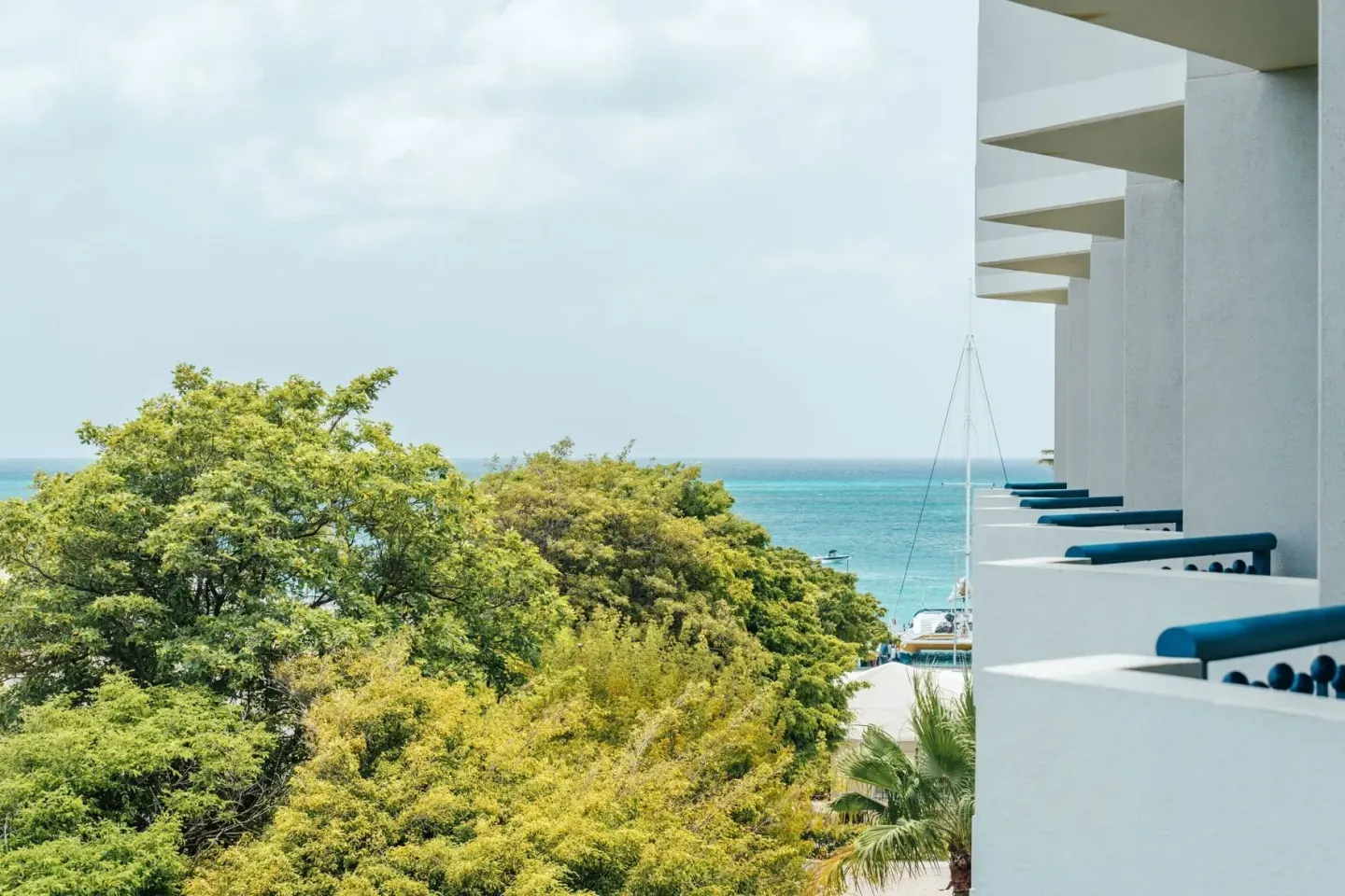 Partial ocean view room balcony scene with treetops and sea at Hilton Aruba Caribbean Resort and Casino.