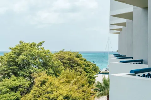 Partial ocean view room balcony scene with treetops and sea at Hilton Aruba Caribbean Resort and Casino.