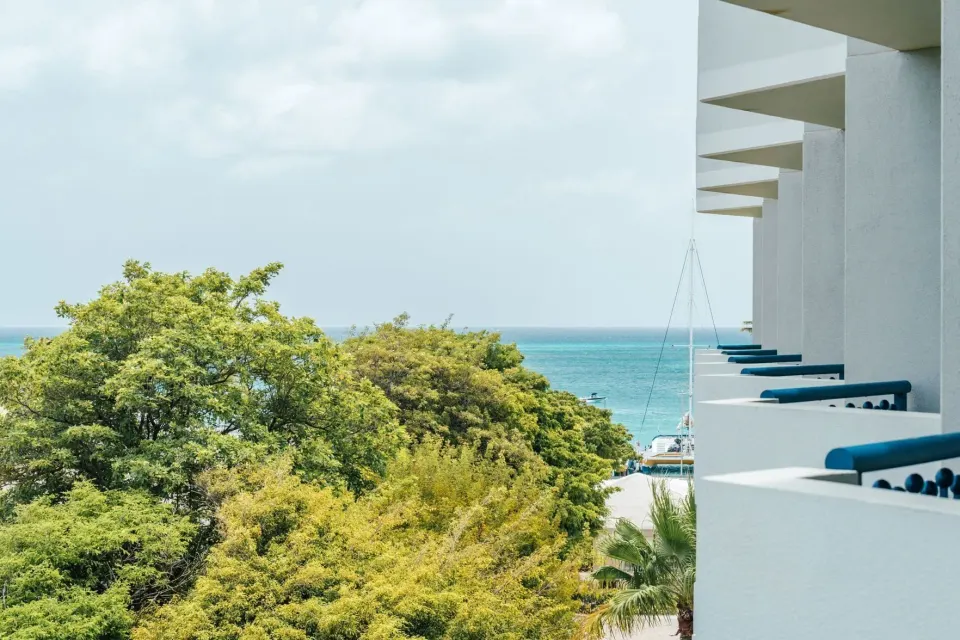 Partial ocean view room balcony scene with treetops and sea at Hilton Aruba Caribbean Resort and Casino.