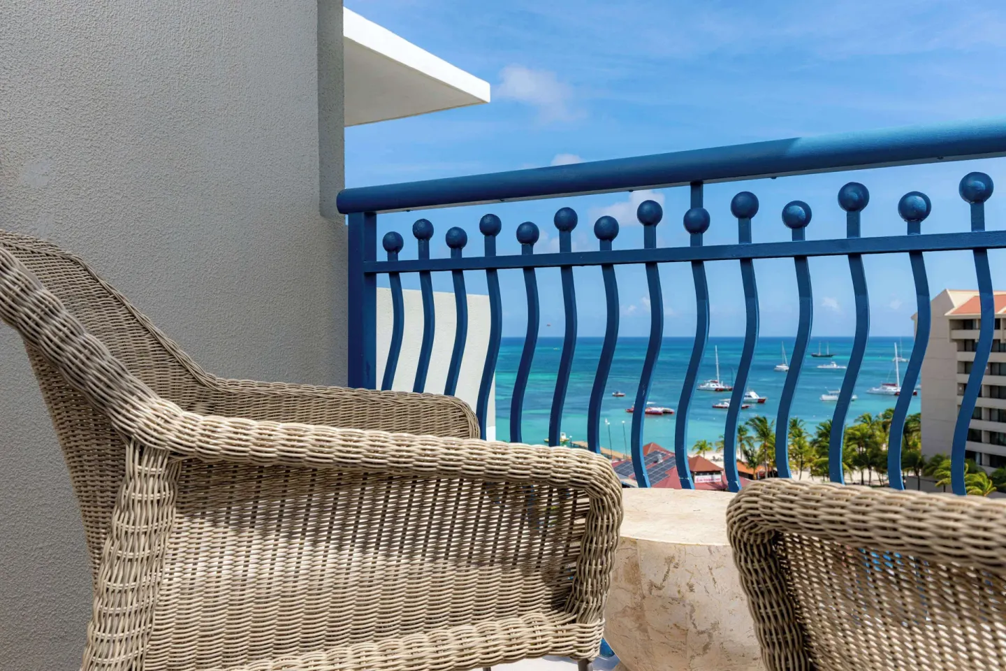 Palm Beach Club room balcony with wicker chairs and ocean view at Hilton Aruba Caribbean Resort and Casino.